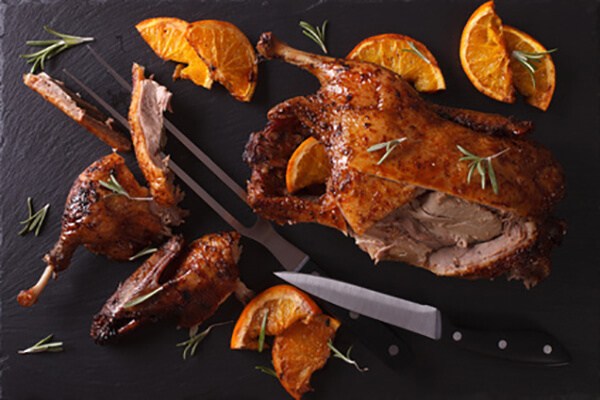 Cutting the roast duck and oranges on a slate board horizontal